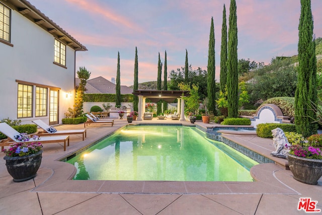 pool at dusk with a patio area