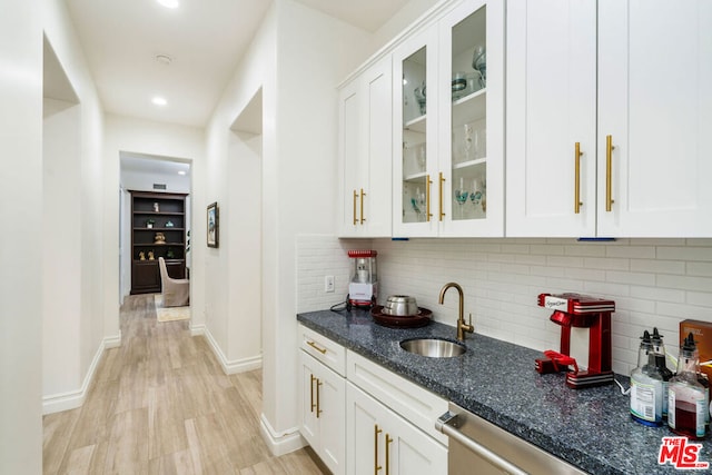 bar with white cabinets, sink, light hardwood / wood-style flooring, decorative backsplash, and dark stone countertops