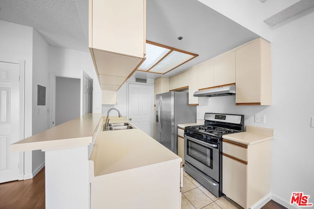 kitchen with sink, light hardwood / wood-style flooring, a textured ceiling, appliances with stainless steel finishes, and cream cabinetry