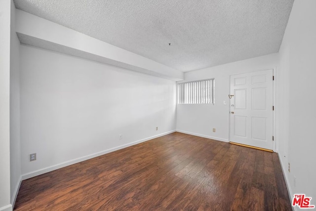 spare room with dark hardwood / wood-style flooring and a textured ceiling