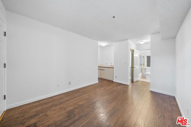 unfurnished room featuring sink, dark hardwood / wood-style flooring, and a textured ceiling