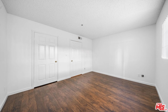 unfurnished bedroom featuring a textured ceiling and dark wood-type flooring