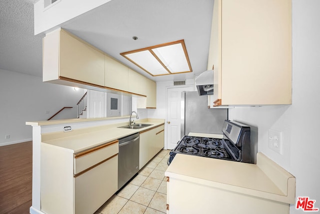 kitchen featuring kitchen peninsula, appliances with stainless steel finishes, premium range hood, sink, and light tile patterned floors