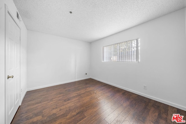 spare room with dark hardwood / wood-style flooring and a textured ceiling