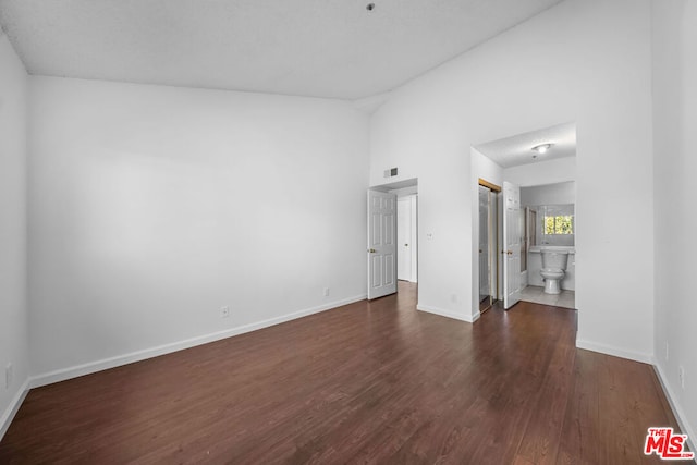 spare room with dark hardwood / wood-style floors and high vaulted ceiling