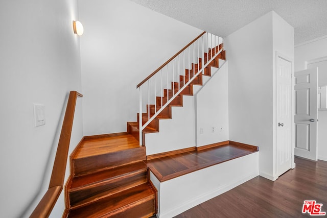 stairs with wood-type flooring and a textured ceiling