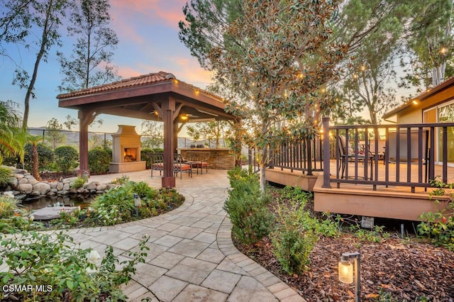 patio terrace at dusk with a deck and exterior fireplace