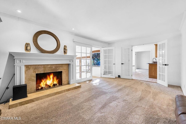 unfurnished living room with crown molding, a premium fireplace, french doors, and light colored carpet