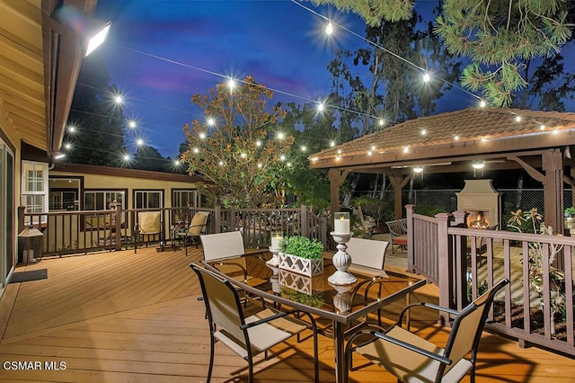 deck at dusk featuring an outdoor fireplace