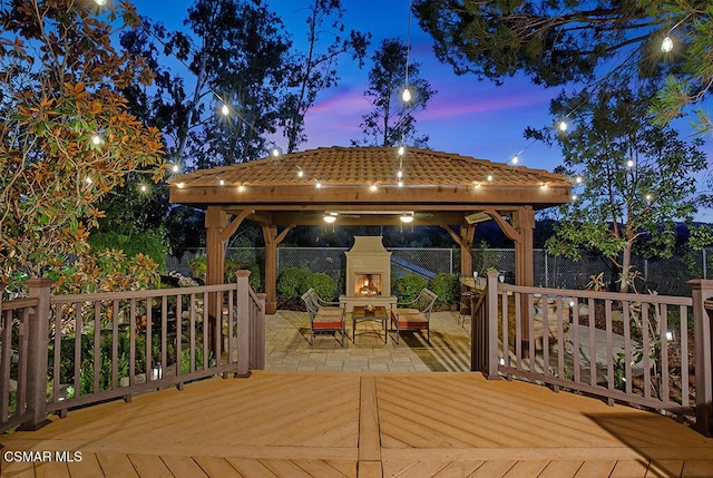 deck at dusk with a gazebo and an outdoor fireplace