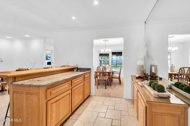 kitchen with sink, an inviting chandelier, light colored carpet, pendant lighting, and ornamental molding