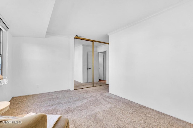 unfurnished bedroom with carpet flooring, a closet, and ornamental molding