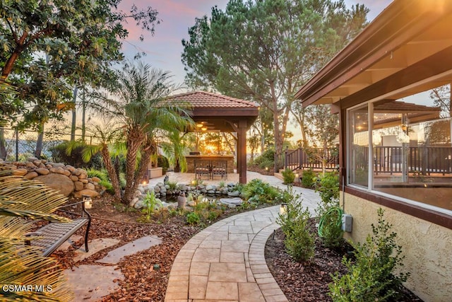 yard at dusk featuring a gazebo, a patio area, and a bar