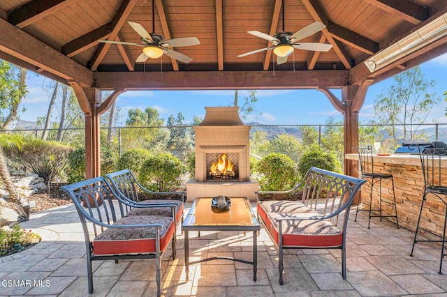 view of patio / terrace featuring a gazebo, ceiling fan, and an outdoor fireplace