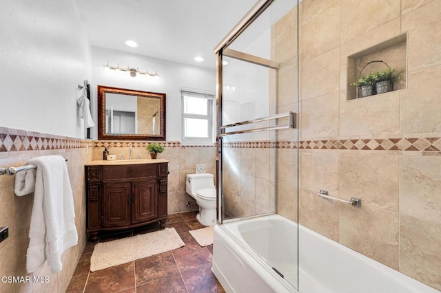 full bathroom with tile patterned flooring, combined bath / shower with glass door, toilet, vanity, and tile walls