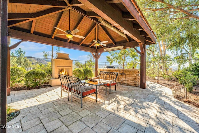 view of patio with ceiling fan, an outdoor bar, and an outdoor fireplace