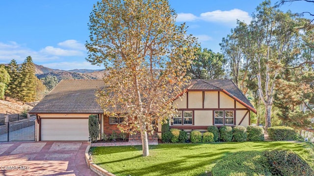 tudor house featuring a mountain view, a garage, and a front lawn