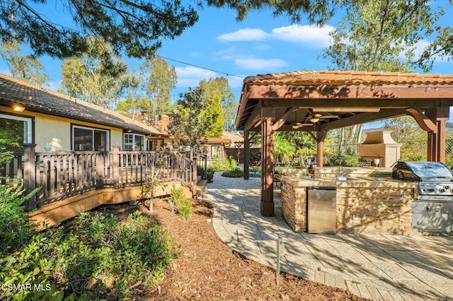 view of yard with a patio area, ceiling fan, an outdoor kitchen, and a deck