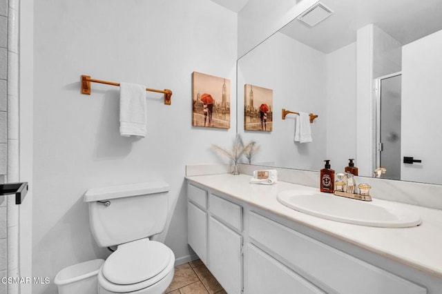 bathroom with tile patterned flooring, vanity, toilet, and walk in shower