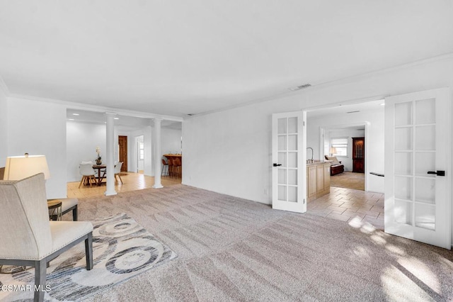 unfurnished room featuring light colored carpet, ornate columns, crown molding, and french doors