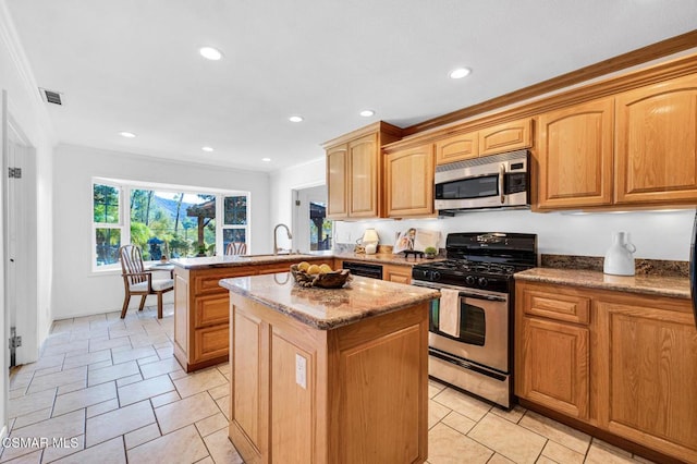 kitchen featuring kitchen peninsula, light stone countertops, stainless steel appliances, sink, and a center island