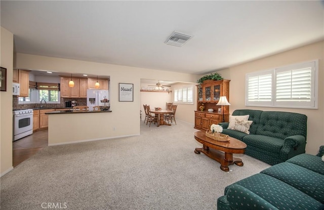 living room with light carpet, ceiling fan, and sink