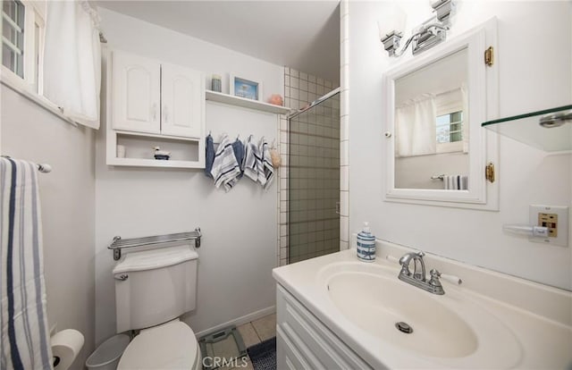 bathroom with tiled shower, vanity, and toilet