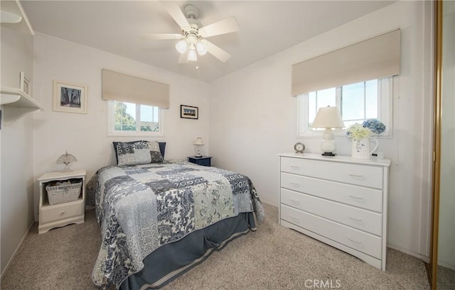 bedroom featuring ceiling fan, light carpet, and multiple windows