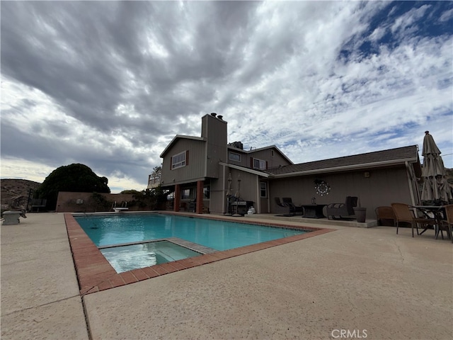 view of swimming pool featuring a patio and an in ground hot tub