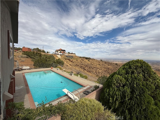 view of swimming pool with a patio area and a diving board