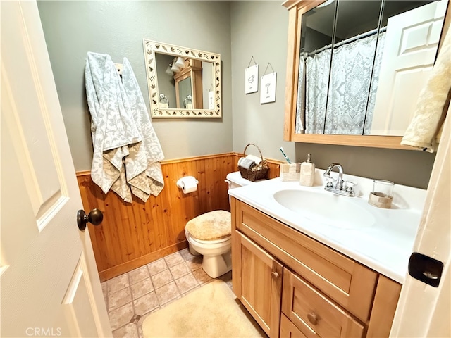 bathroom featuring vanity, toilet, wood walls, and tile patterned floors