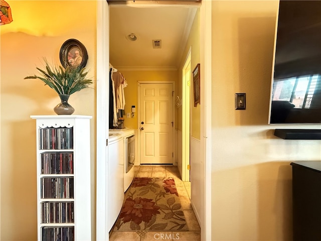 hallway with ornamental molding, washing machine and dryer, and light tile patterned floors