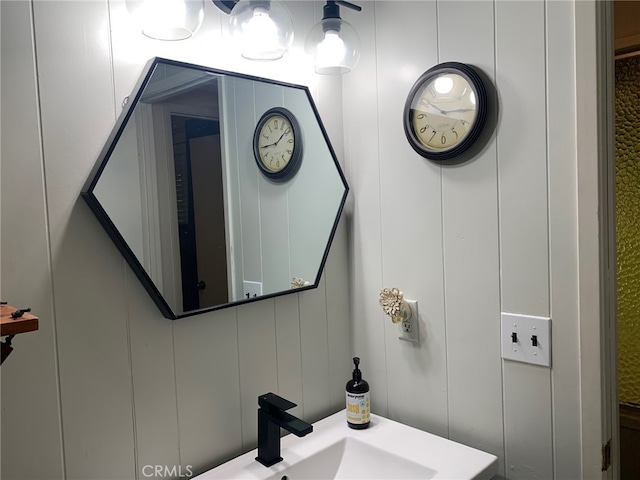 bathroom featuring wood walls and sink