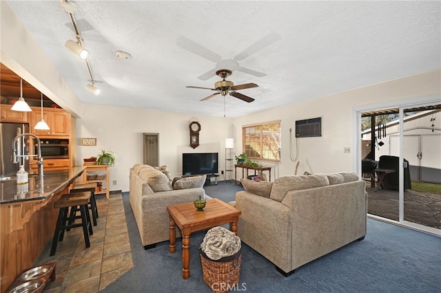 carpeted living room with a textured ceiling, rail lighting, a wall mounted AC, and ceiling fan