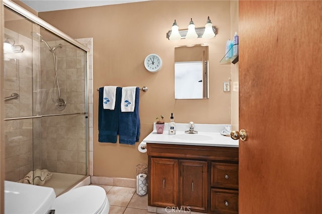 bathroom with tile patterned floors, vanity, a shower with shower door, and toilet