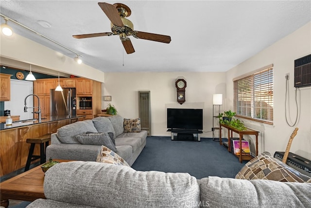 living room with dark carpet, track lighting, an AC wall unit, sink, and ceiling fan