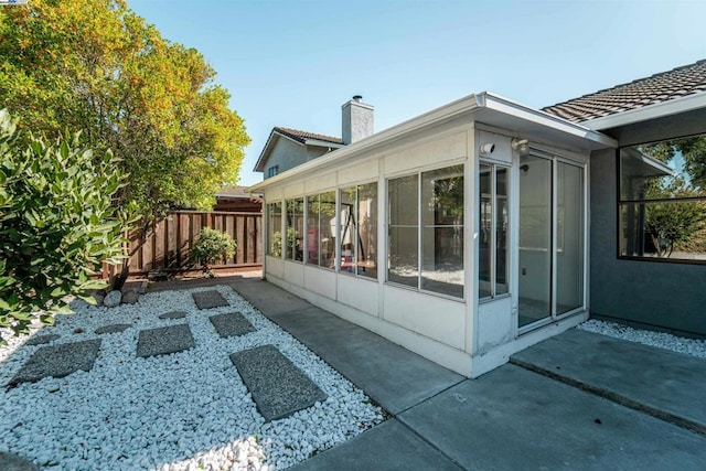 view of side of property featuring a patio area and a sunroom