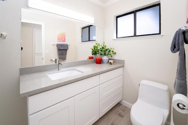 bathroom with crown molding, vanity, wood-type flooring, and toilet