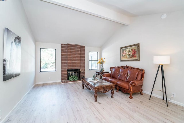 living room featuring vaulted ceiling with beams, a brick fireplace, plenty of natural light, and light hardwood / wood-style flooring