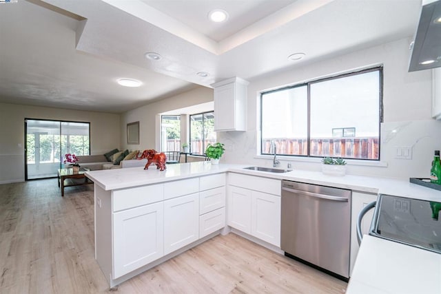 kitchen with kitchen peninsula, stainless steel dishwasher, sink, light hardwood / wood-style flooring, and white cabinets