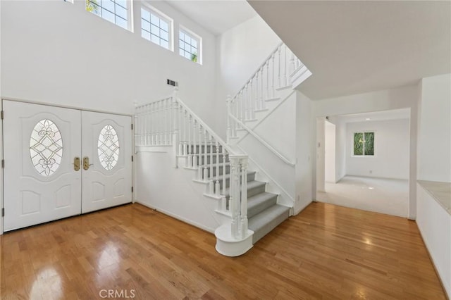 foyer featuring a healthy amount of sunlight, a high ceiling, and hardwood / wood-style flooring