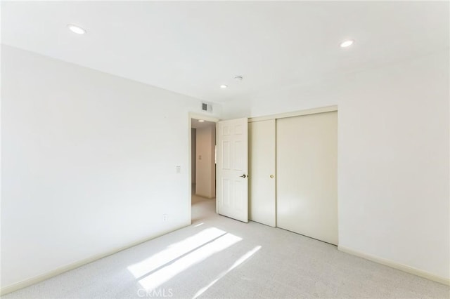 unfurnished bedroom featuring light carpet and a closet