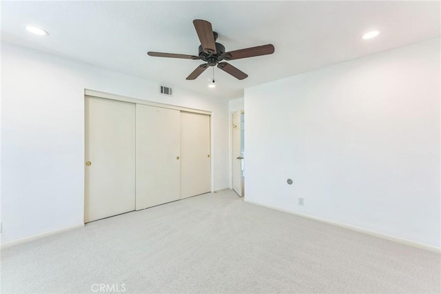 unfurnished bedroom featuring ceiling fan, light carpet, and a closet