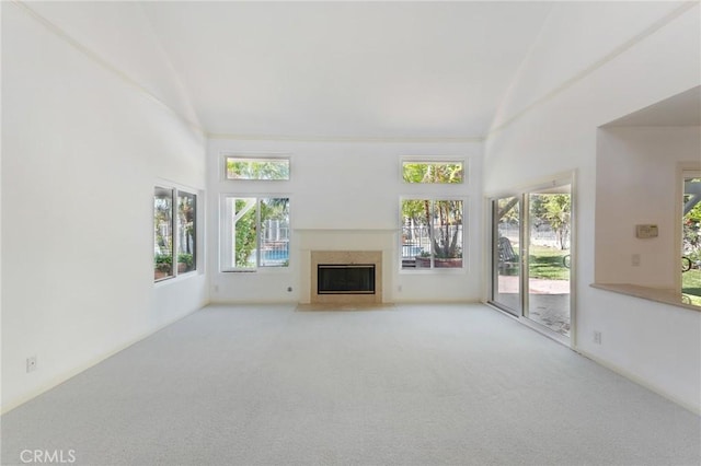 unfurnished living room featuring light colored carpet, vaulted ceiling, and a wealth of natural light