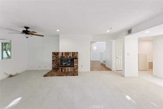 carpeted living room with a brick fireplace and ceiling fan