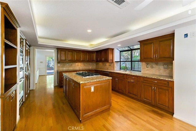 kitchen with light stone countertops, a center island, light hardwood / wood-style floors, and appliances with stainless steel finishes