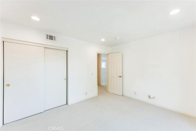 unfurnished bedroom with light carpet and a closet