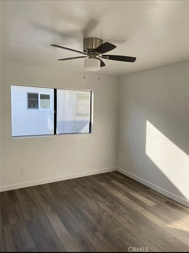 empty room featuring dark wood-type flooring and ceiling fan