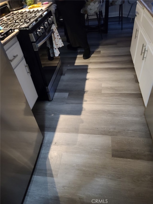 interior details with black range with gas cooktop, hardwood / wood-style floors, a fire pit, and white cabinets