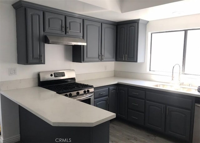 kitchen with sink, dark wood-type flooring, stainless steel gas range, and kitchen peninsula